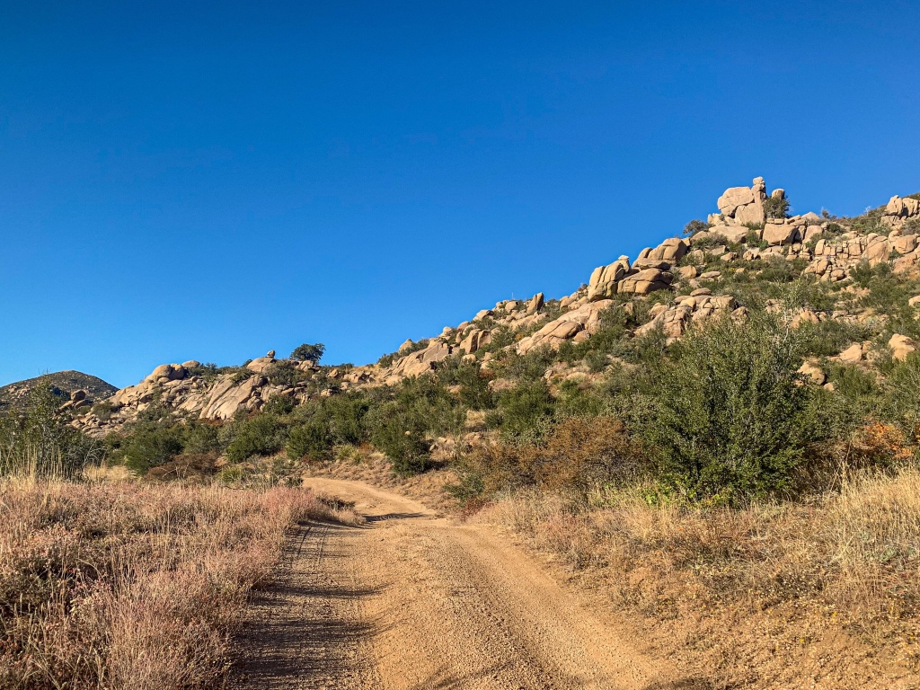 Tan sedimentary rock jumbles sit among green scrub brush and brown ricegrass along the Pine Mountain ridgeline in the southern Mazatzal Mountains, thruhiking the Arizona Trail.